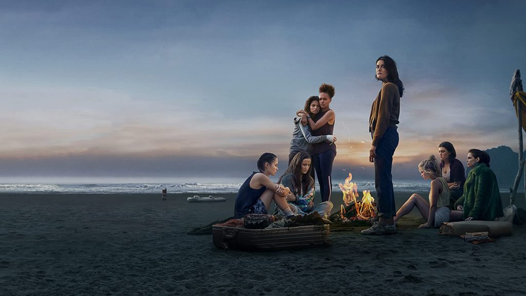 A group of teen girls huddle around a campfire